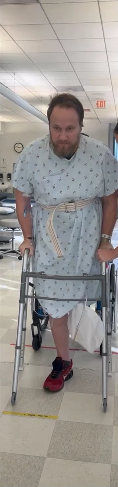 Travis Boles learning to walk again with a walker in the hospital